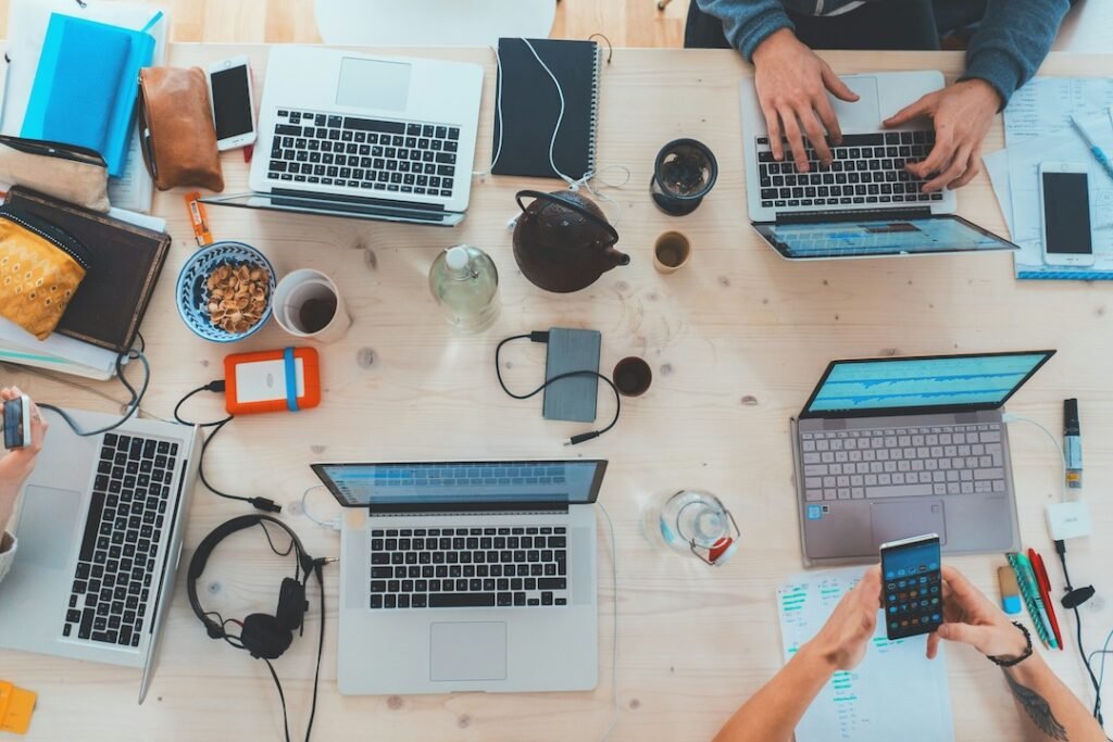 Vista cenital de un equipo colaborando con portátiles en una oficina flexible, un factor que impulsa la innovación y la retención de talento en startups