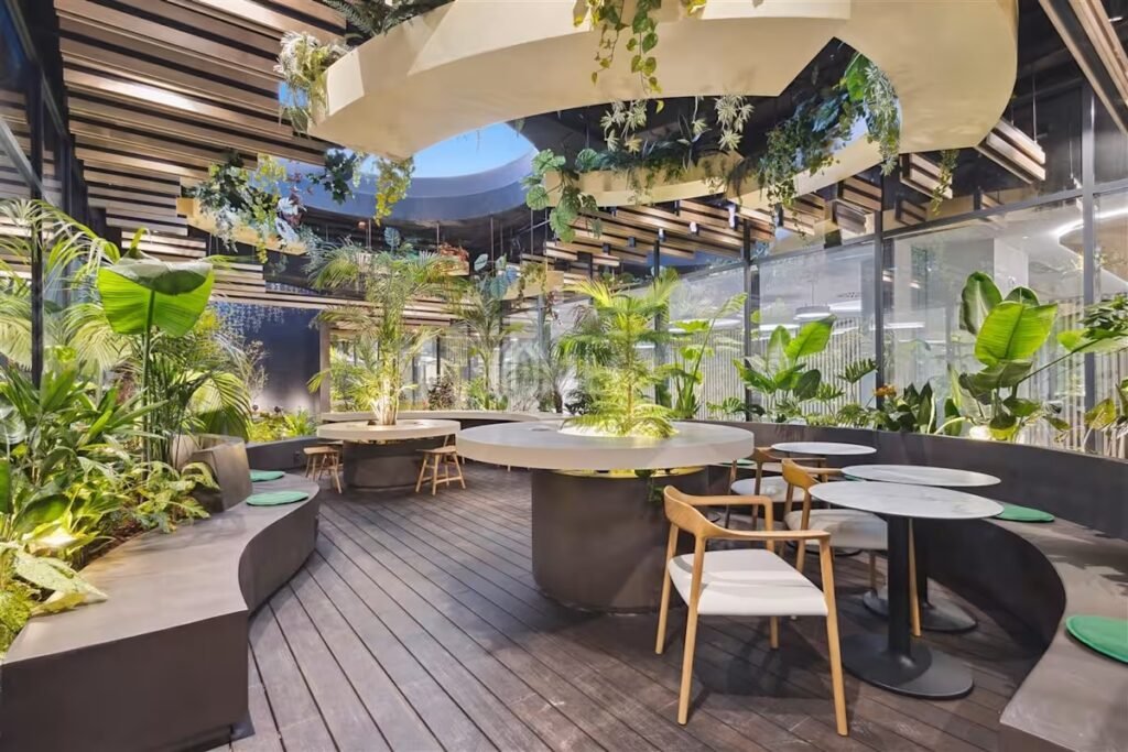 Zona social en una oficina con diseño biofílico, que integra plantas y materiales naturales para fomentar el bienestar y la cultura de empresa.