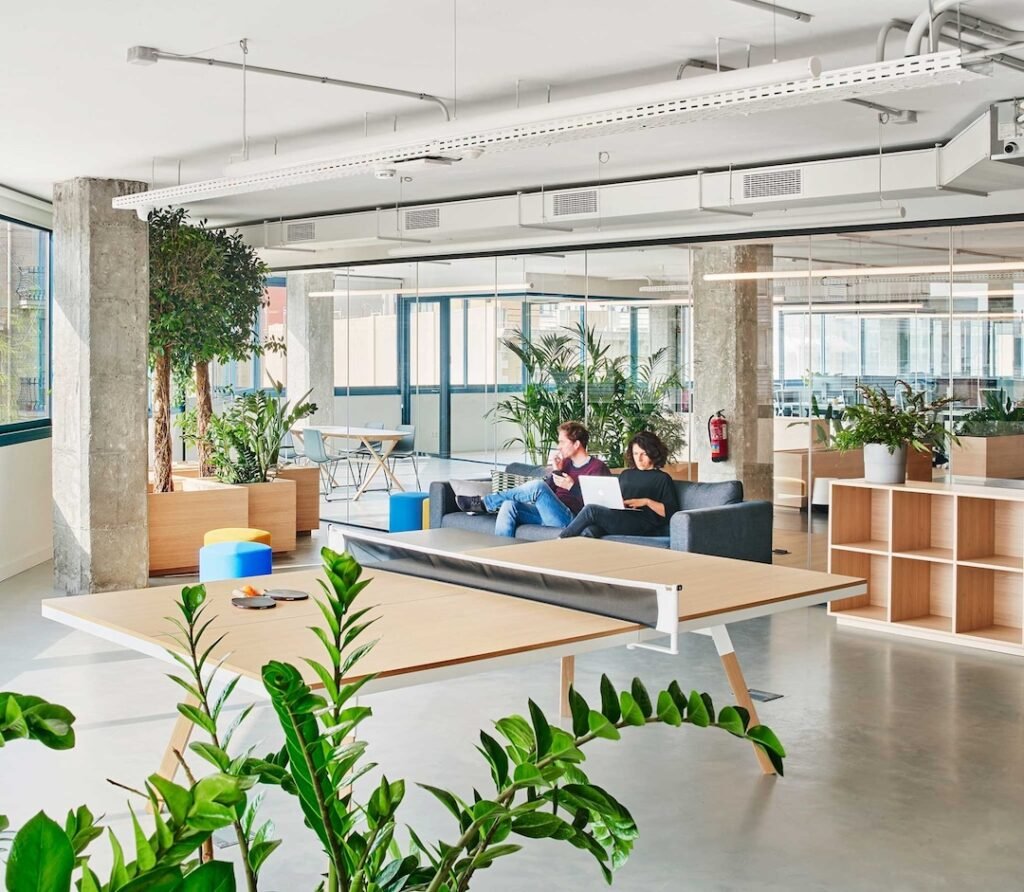 Oficina de startup con diseño abierto y una mesa de ping-pong, reflejando una cultura de empresa moderna que equilibra trabajo y bienestar.