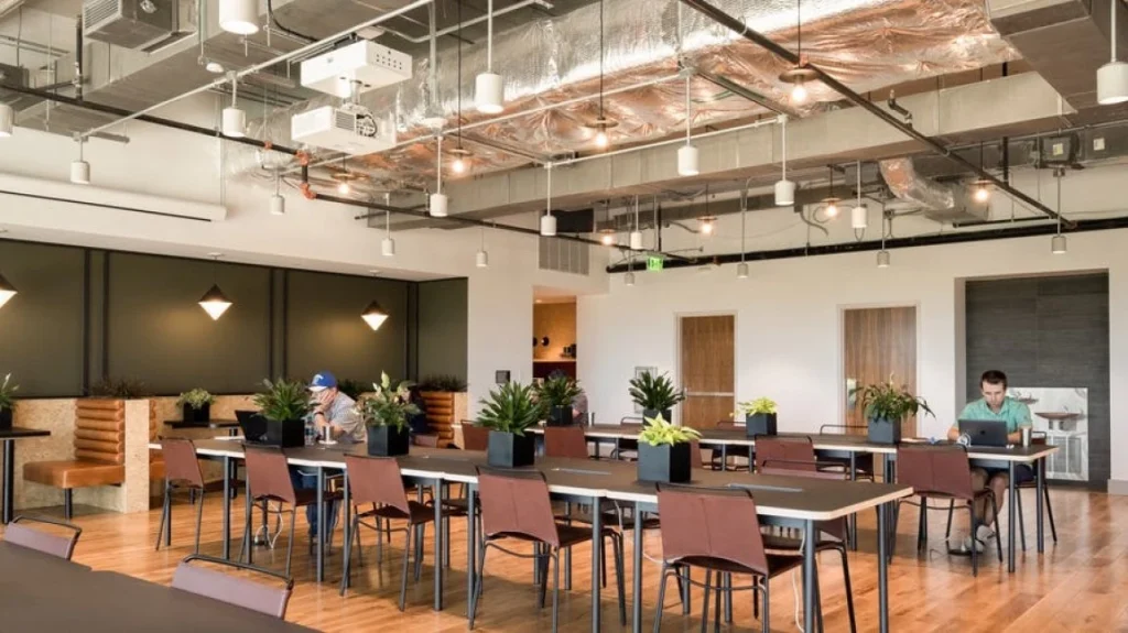 Espacio de trabajo compartido estilo industrial y zonas comunes para networking en WeWork Goya