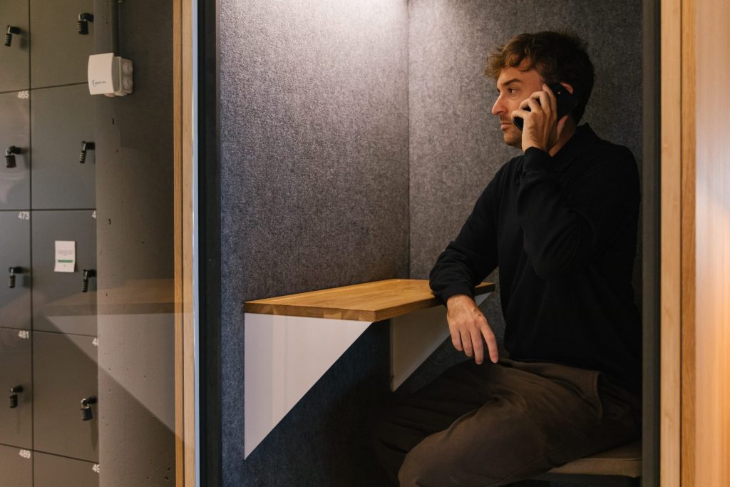Hombre trabajando concentrado dentro de un phone booth o cabina acústica, una solución de diseño para mejorar la acústica y evitar el ruido en la oficina.
