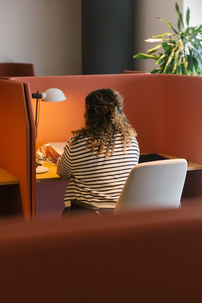 Mujer realizando 'deep work' en una zona de foco con separadores para evitar los problemas de ruido en un coworking.