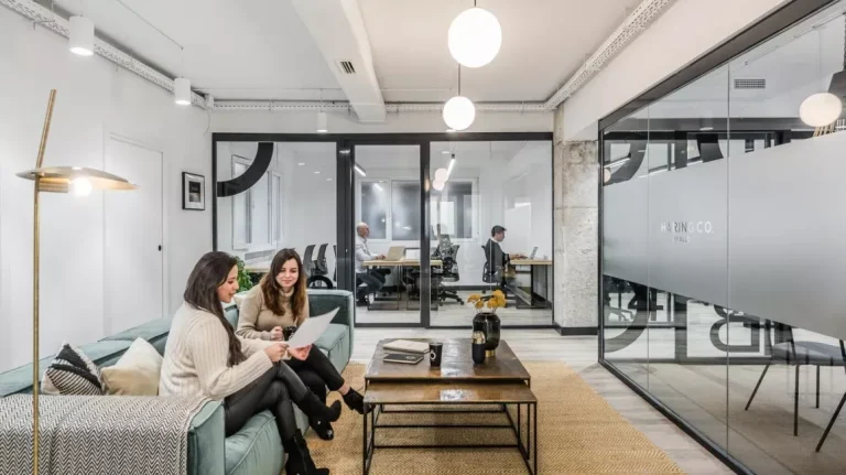 Equipo de trabajo colaborando en la zona lounge de Sharing Co, un espacio de oficina que se siente como una extensión de la cultura de casa.