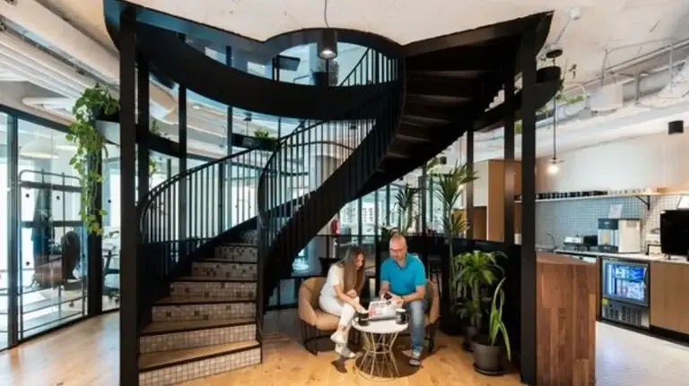 Escalera caracol de diseño moderno y zona de café en WeWork Castellana 43, un entorno de oficina flexible con estándares internacionales.