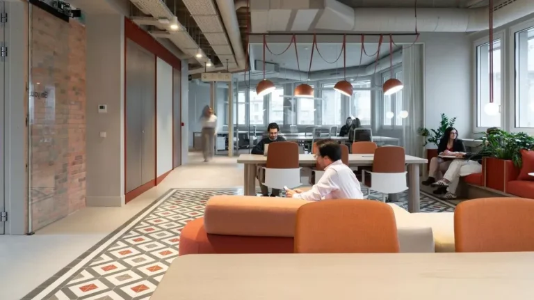 Profesionales trabajando en zona de open space con luz natural y suelos hidráulicos decorativos en NN Pau Claris.