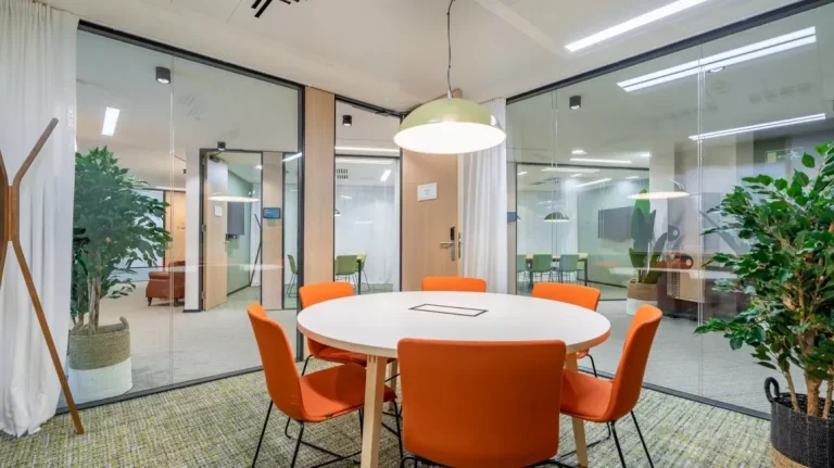 Sala de reuniones pequeña con mesa circular y sillas naranjas en Utopicus Diagonal, ideal para reuniones de equipo y captación de talento.