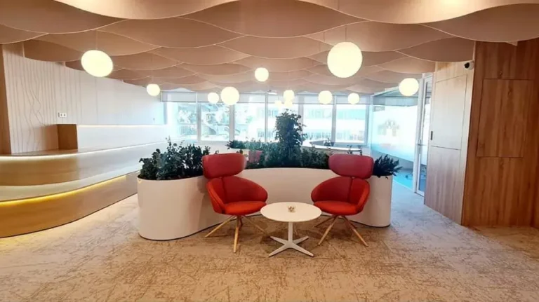 Área lounge de Networkia Diagonal con butacas de diseño rojo, iluminación ambiental y techo decorativo moderno.